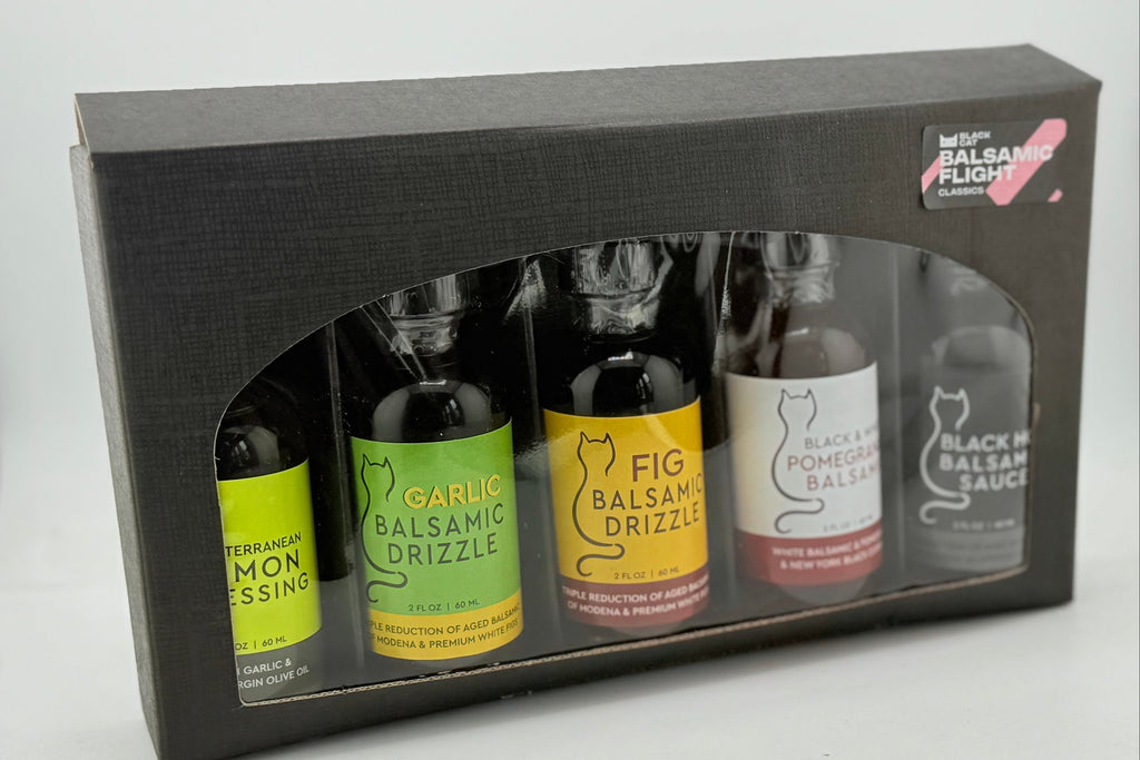 Set of mini balsamic bottles in a black gift box on a white background